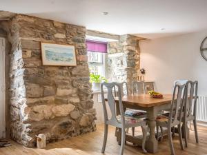 ein Esszimmer mit einem Tisch und Stühlen an einer Steinmauer in der Unterkunft Bwlchgroes in Dinas
