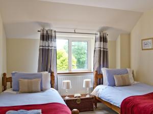 two beds in a room with a window at The Old Mill in Bampton +2 photos