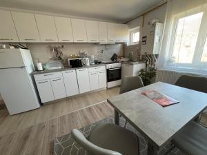 a kitchen with white cabinets and a table with chairs at Apartament Hanna - Straja in Uricani