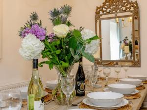 a table with a vase of flowers and wine bottles at The Water Mill in Bradbourne +41 photos