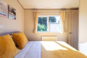 a bedroom with a bed with yellow pillows and a window at 3 Bedroom Caravan-Seton Sands in Port Seton