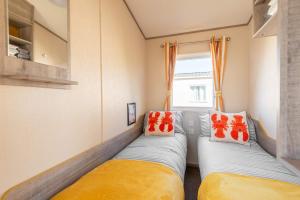 two beds in a small room with a window at 3 Bedroom Caravan-Seton Sands in Port Seton