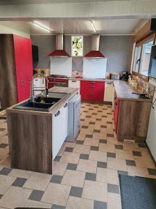 a large kitchen with red cabinets and white appliances at Gîte du Tronquoy in Aix-en-Ergny