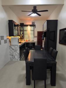 a kitchen with a dining room table and a ceiling fan at Coach homestay 2 in Kuantan