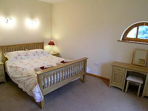 FilbyにあるThe Stablesのベッドと机と窓のある寝室