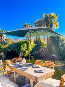 a wooden table with an umbrella in a yard at Casa Tranquilla in Cannobio +52 photos