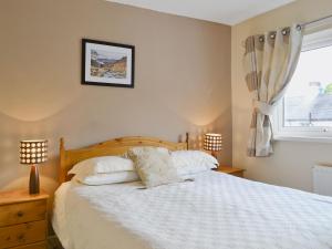 a bedroom with a bed with two lamps and a window at Serendipity in Keswick