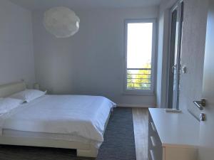 ein weißes Schlafzimmer mit einem Bett und einem Fenster in der Unterkunft Villa Franka 1 in Brela