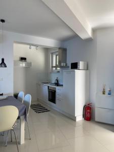 eine Küche mit weißen Geräten sowie einem Tisch und Stühlen in der Unterkunft Villa Franka 1 in Brela