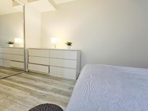 a white bedroom with a bed and a mirror at Garden Ave Suite 3 Mins to Hwy 403 in Brantford