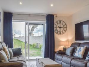 een woonkamer met een bank en een klok aan de muur bij Seascape in Sandown