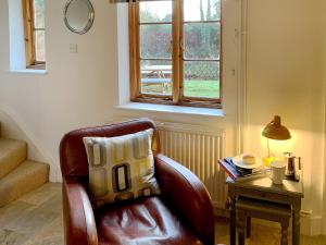 ein Ledersessel mit einem Kissen neben einem Tisch in der Unterkunft Moorhen Cottage in Hollingbourne + 23 Fotos