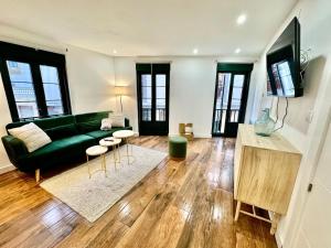 a living room with a green couch and wooden floors at Gestviva Casa Urbanin I in Cudillero