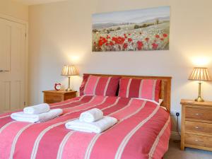een slaapkamer met een rood en wit bed met handdoeken erop bij Croft Cottage 1 - Uk10587 in Stillington +4 foto's