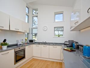 a white kitchen with white cabinets and windows at Una Argentum 61 in Carbis Bay