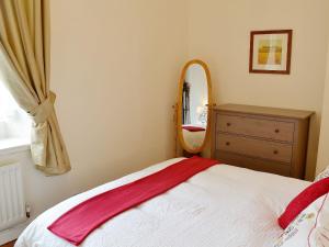 a bedroom with a bed and a dresser and a mirror at The School House - 28445 in Middleton in Teesdale
