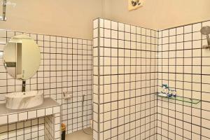a white tiled bathroom with a mirror and a sink at Na Bua Villa Chiangrai in Ban Rim Lao