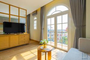 フーコックにあるHD Hotel Sunset Townのテレビと大きな窓のあるリビングルーム