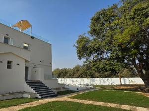 a white building with stairs next to a tree at Nakhil Pyramids Resort in Cairo +44 photos