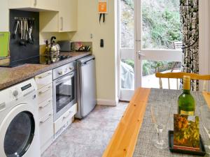eine Küche mit einer Waschmaschine und einem Tisch in der Unterkunft Heale Cottage - 28087 in Littleham