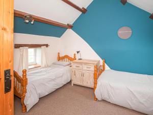 two twin beds in a room with blue walls at Cwm Nantcol Barn in Llanbedr