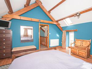 a bedroom with a blue wall with a bed and a mirror at Cwm Nantcol Barn in Llanbedr