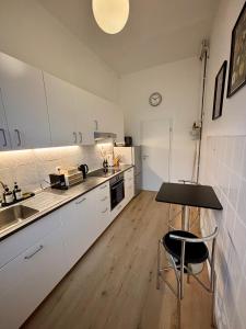 ブラウンシュヴァイクにあるEasyPark City Suiteの白いキャビネットとテーブルと椅子のあるキッチン +8枚の写真