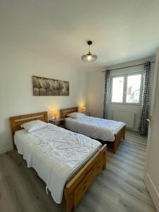 Appartement tout confort - Idéal pour les familles في فوجير: سريرين في غرفة نوم بها مصباحين ونافذة