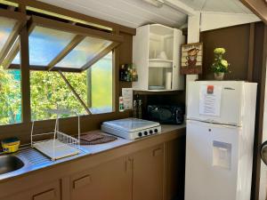 Una cocina con un refrigerador blanco y un fregadero. en Fare Miti Ora Moorea - Bungalow mitoyen, en Hauru