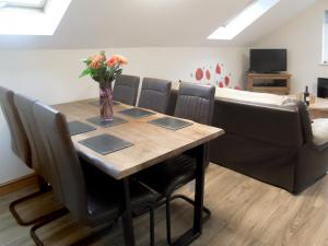 a dining room table with chairs and a vase of flowers at Ysgubor Uchaf - 29517 in Fairbourne