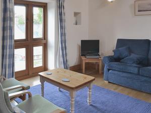 a living room with a blue couch and a coffee table at The Threshing Barn in Westbury-sub-Mendip