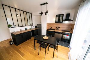 a kitchen with a black table and chairs in a room at T3 BROOKLYN - Luminous - Central - Wifi - Parking in Nanterre