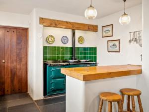 Saint FlorenceにあるWorthy Houseの緑色のストーブと2つのスツールを備えたキッチン