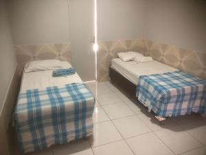 a room with two beds and a tiled floor at Vivenda Hotel in Arapiraca