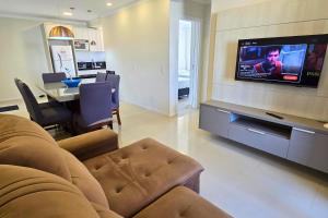 a living room with a couch and a tv on a wall at Apartamento no Coração de Bombinhas in Bombinhas