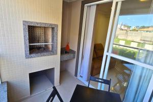 a room with a brick fireplace with a table and a window at Apartamento no Coração de Bombinhas in Bombinhas