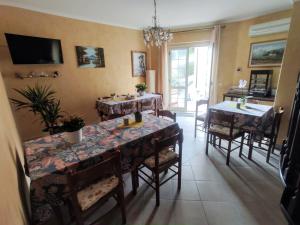 uma sala de jantar com mesas e cadeiras e uma televisão em Vicky's B&B by V em Papasidero