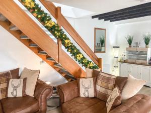un salon avec des canapés et un escalier fleuri dans l'établissement Holly Cottage, à Palnackie
