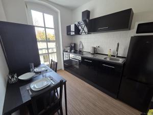 a kitchen with black cabinets and a table with two sinks at Stylische Flat1 mit französischem Balkon1 all-in 5G in Gera +7 photos