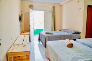 a bedroom with two beds and a door to a balcony at Pousada Residência Lençóis in Barreirinhas +67 photos