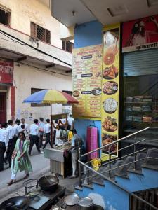 un groupe de personnes passant devant un stand de nourriture avec un parapluie dans l'établissement Sonawala Heritage Inn, à Varanasi