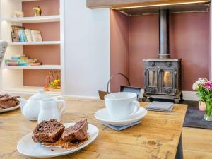 a table with two plates of bread and cups and a stove at Penlon Cwrws in Llangynllo
