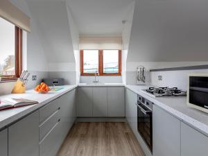 a white kitchen with white cabinets and a stove at Coot in Wroxham