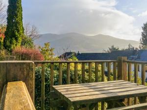 a wooden bench on a wooden fence with mountains in the background at Thwaite Hill Cottage in Braithwaite +2 photos