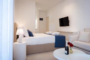ein Schlafzimmer mit einem Bett, einer Couch und einem Fernseher in der Unterkunft Afissos Blu Hotel in Áfissos
