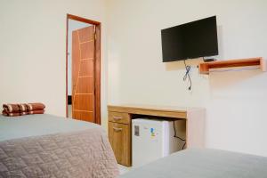 a bedroom with a bed and a tv on the wall at Residência Lençóis Pousada in Barreirinhas