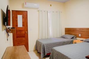 a hotel room with two beds and a window at Residência Lençóis Pousada in Barreirinhas +49 photos
