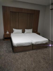 Un dormitorio con una cama grande con sábanas y almohadas blancas. en شقق رفاء, en Al Ula