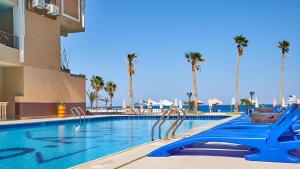 a swimming pool with palm trees and blue slides at Juliana Beach Elite Queen T Collection in Hurghada