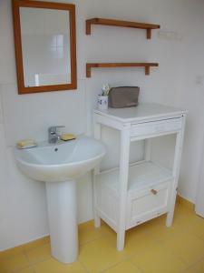 a bathroom with a white sink and a mirror at Maison d'Aude in Brignogan-Plage